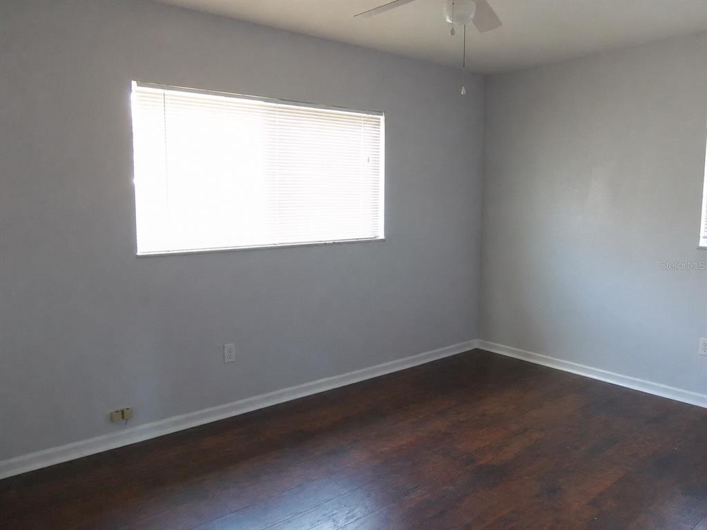 A bedroom with dark wood-look flooring, light gray walls, a white closet, and a window — 1427 PLEASANT PLACE, LAKELAND, FL