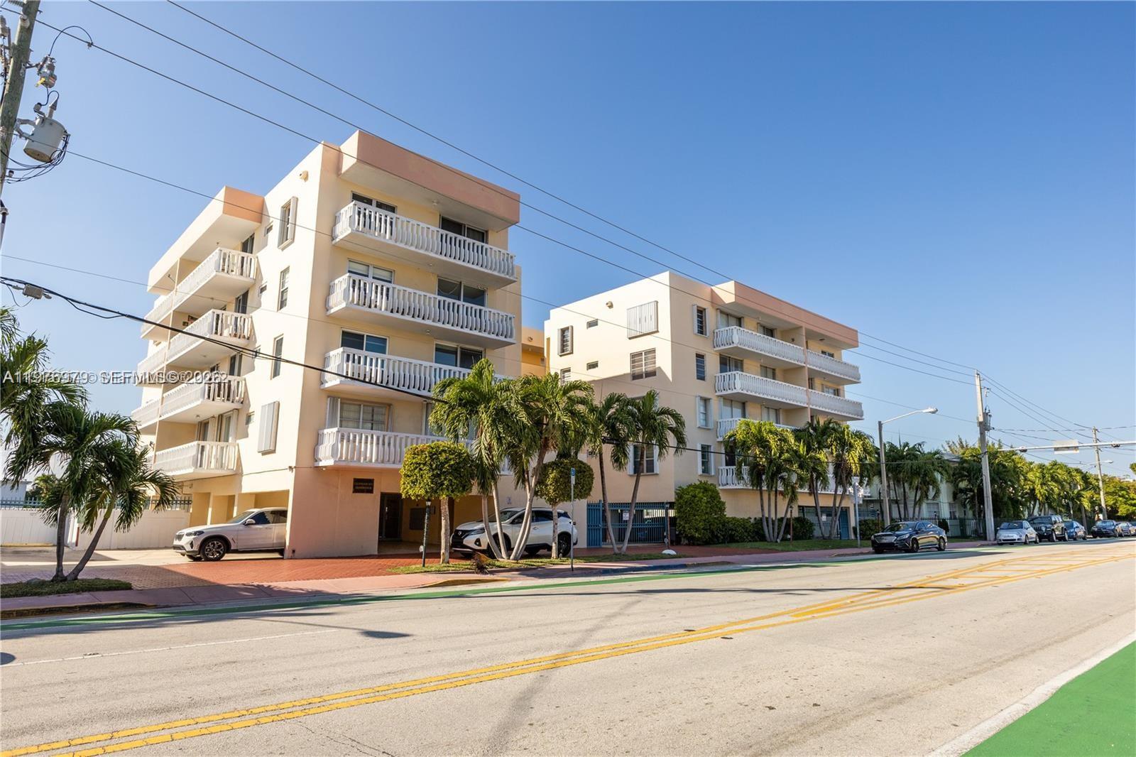 A multi-story white apartment building features stacked balconies and a ground-level parking area — 8530 Byron Ave # 402, Miami Beach FL 33141, MIAMI BEACH, FL