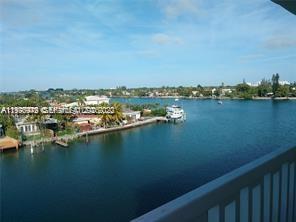 A multi-story white apartment building with blue accents sits along a waterfront canal — 8530 Byron Ave # 402, Miami Beach FL 33141, MIAMI BEACH, FL
