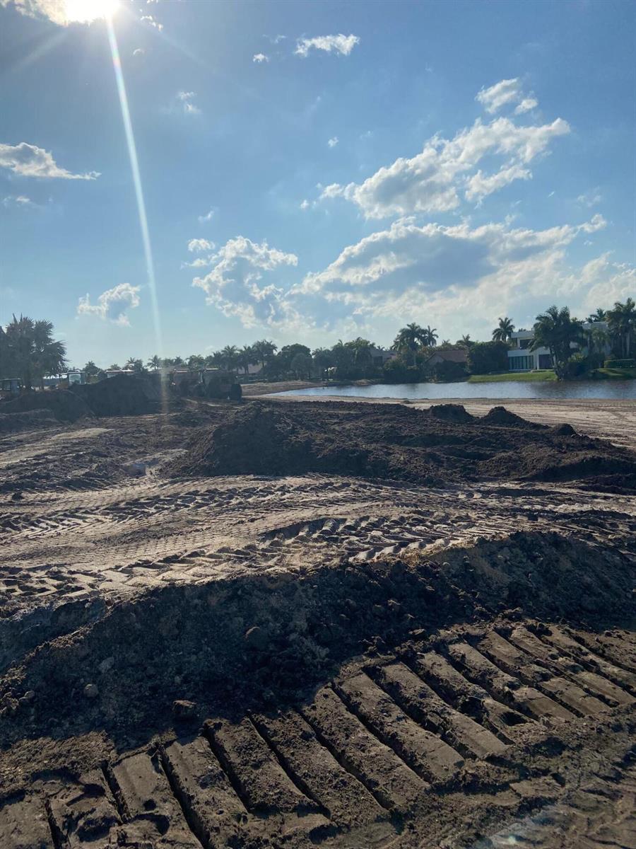 A construction site with piles of dirt and tire tracks overlooking a lake and trees — 4100 Clint Moore Road, Boca Raton FL 33496, BOCA RATON, FL
