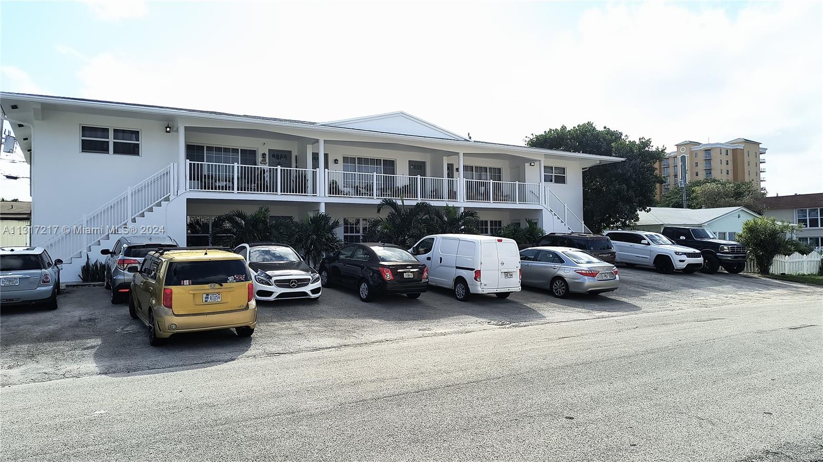 A two-story white apartment building features a balcony and a parking lot with several vehicles — 3212 NE 10th St, Pompano Beach FL 33062, POMPANO BEACH, FL