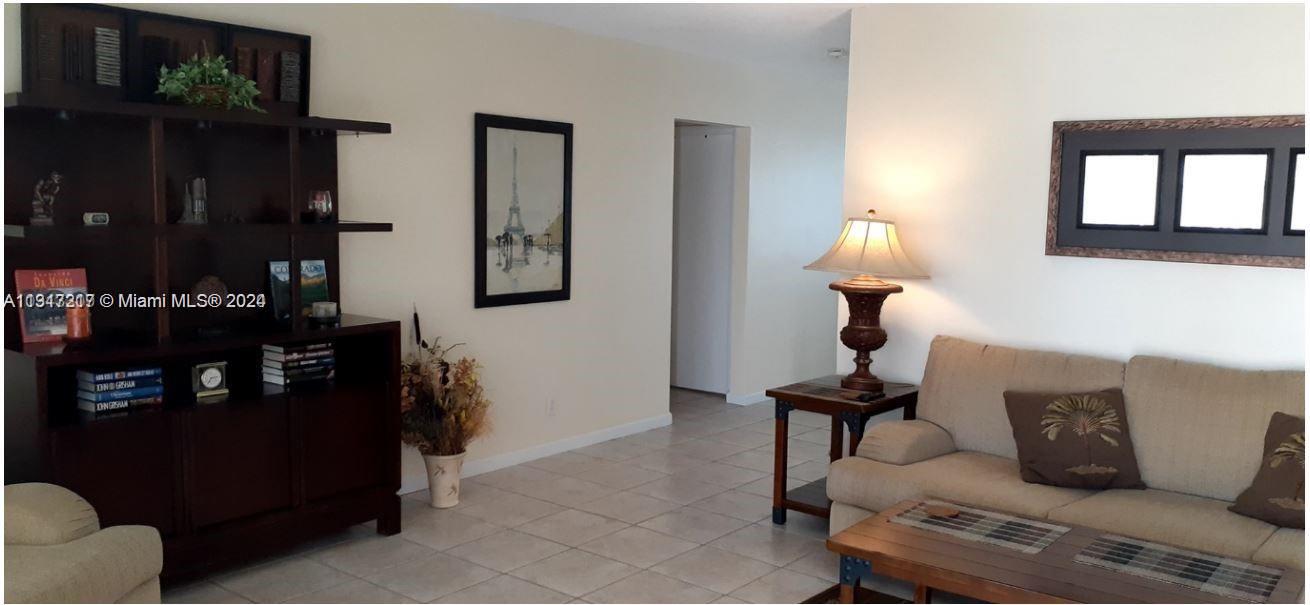A living room features tile flooring, a dark wood bookshelf, and a beige sofa — 3212 NE 10th St, Pompano Beach FL 33062, POMPANO BEACH, FL