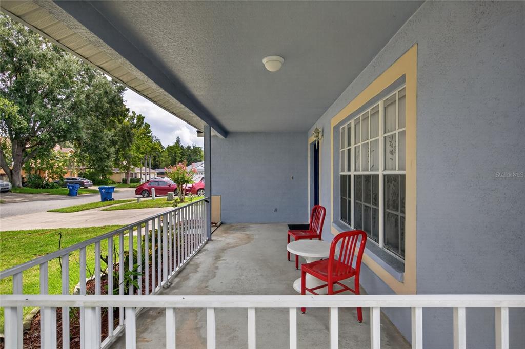 A covered front porch features a concrete floor, white railing, and two red metal chairs — 24331 CROSSCUT ROAD, LUTZ, FL