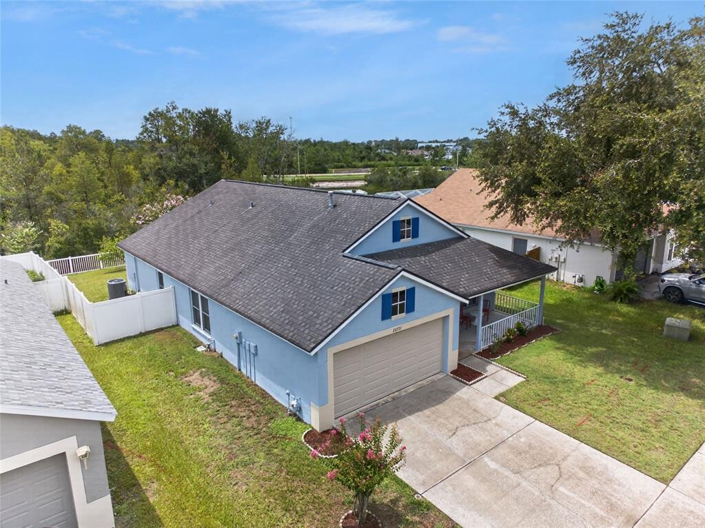 An aerial view shows a light blue house with a dark shingled roof and garage — 24331 CROSSCUT ROAD, LUTZ, FL