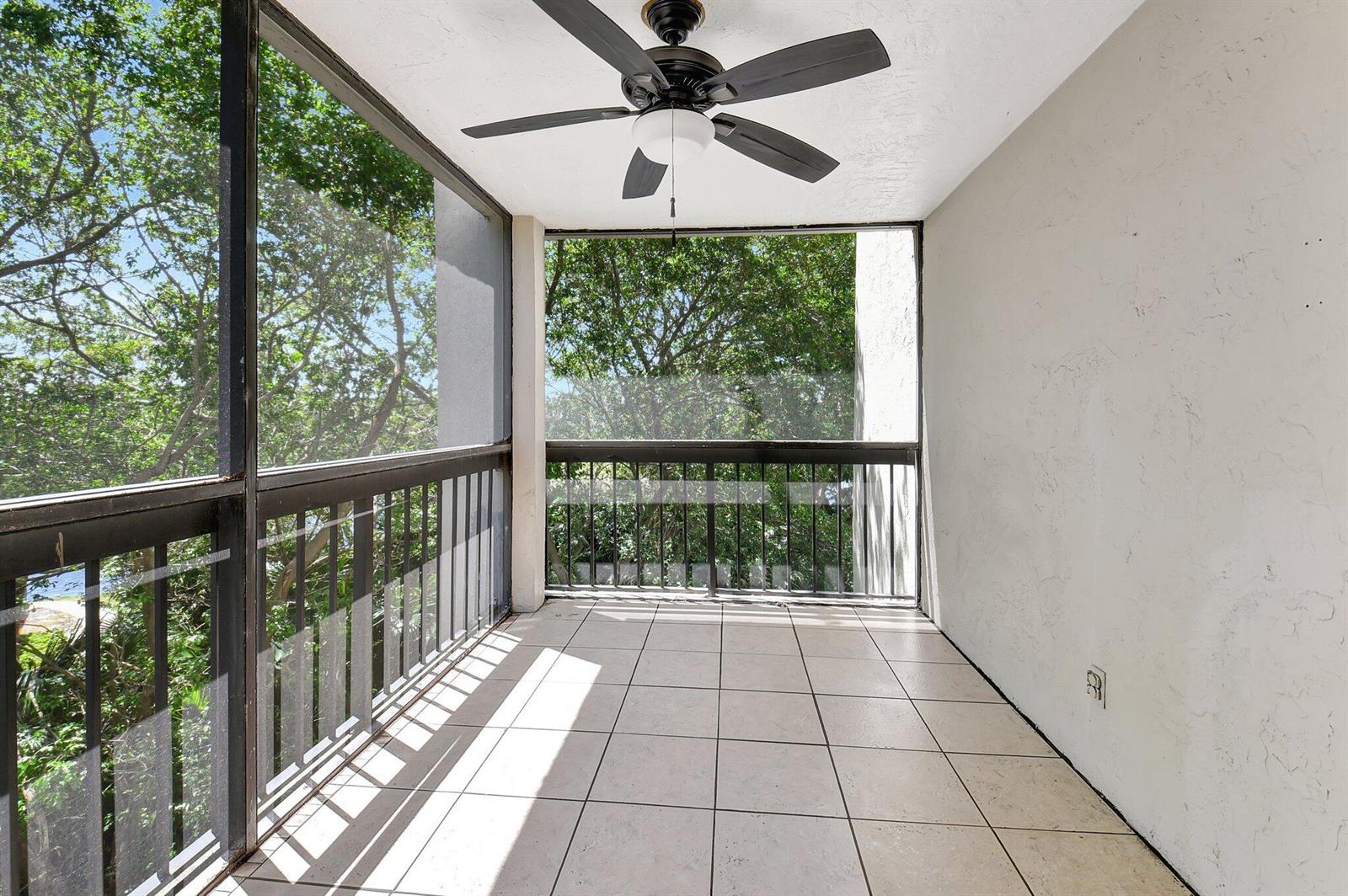 A screened-in balcony features light-colored tile flooring, a ceiling fan, and a metal railing — 820 Lavers Circle # G402, Delray Beach FL 33444, DELRAY BEACH, FL