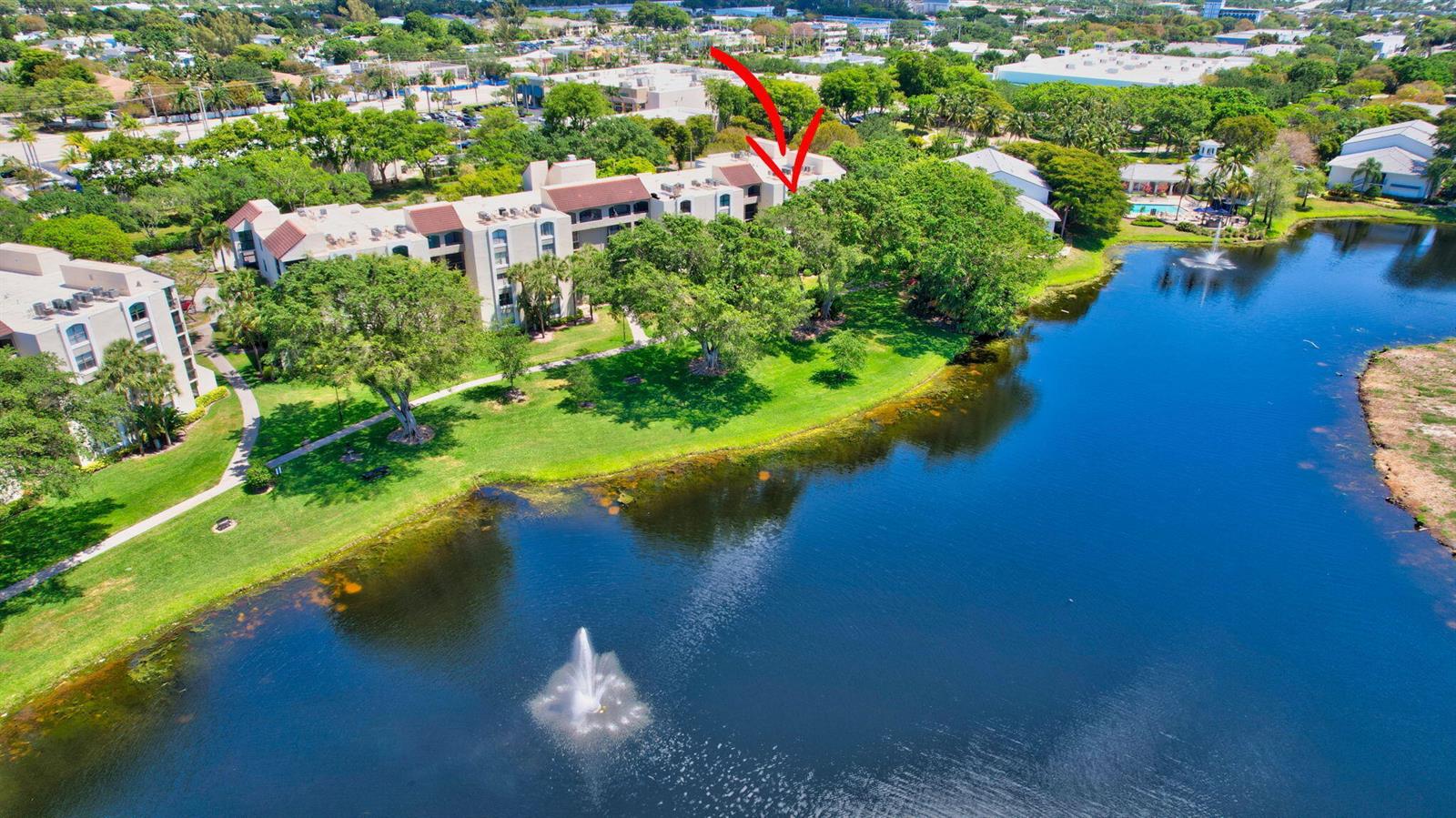 An aerial view shows a multi-story apartment building situated next to a large lake — 820 Lavers Circle # G402, Delray Beach FL 33444, DELRAY BEACH, FL