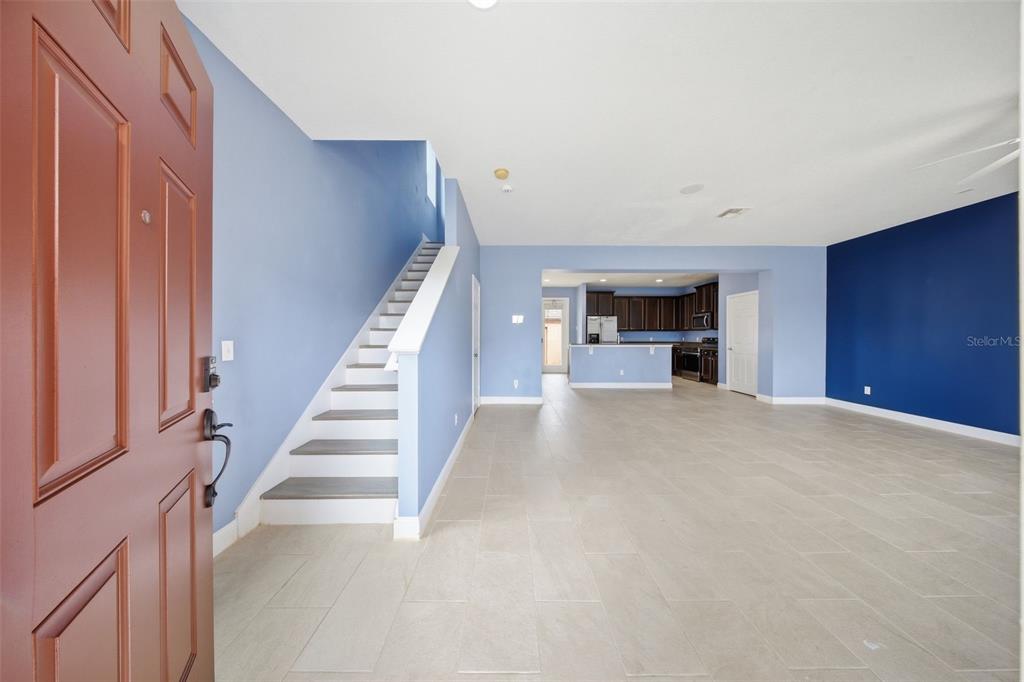 An open-concept living area features light blue walls, a dark blue accent wall, and stairs — 1347 ALSTON BAY BOULEVARD, APOPKA, FL