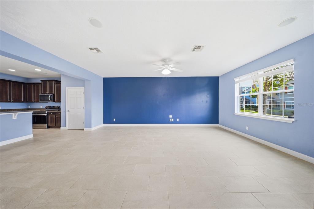 A spacious living room features light blue walls, a dark blue accent wall, and tile flooring — 1347 ALSTON BAY BOULEVARD, APOPKA, FL