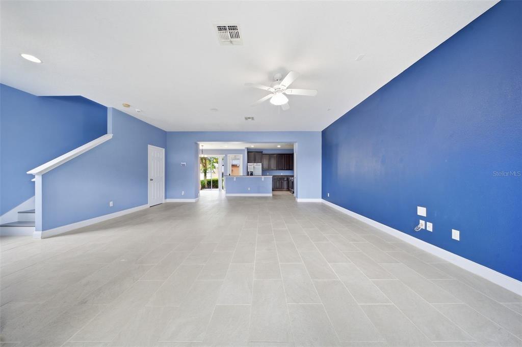 A spacious living room features light blue walls, a large dark blue accent wall, and tile flooring — 1347 ALSTON BAY BOULEVARD, APOPKA, FL