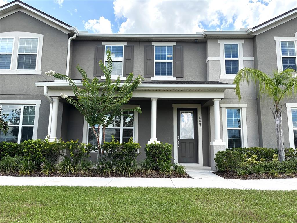 A two-story gray townhouse features a covered front porch, white columns, and dark shutters — 10009 EAGLE ROCK ALLEY, ORLANDO, FL
