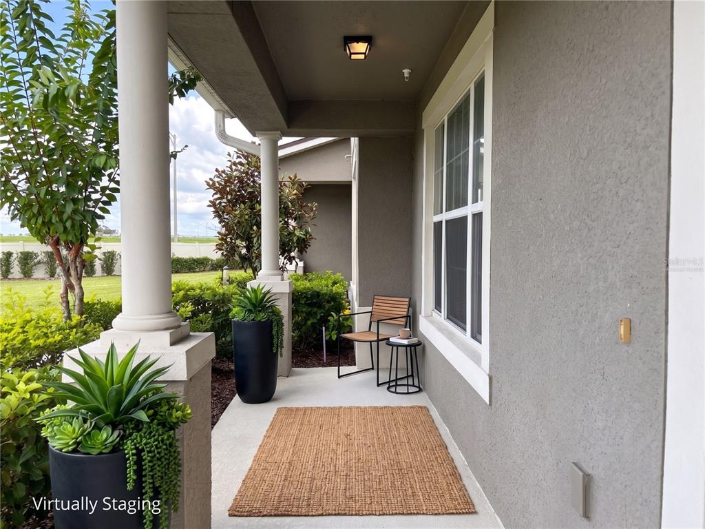 A covered porch features a concrete floor, a rug, a chair, and potted plants — 10009 EAGLE ROCK ALLEY, ORLANDO, FL