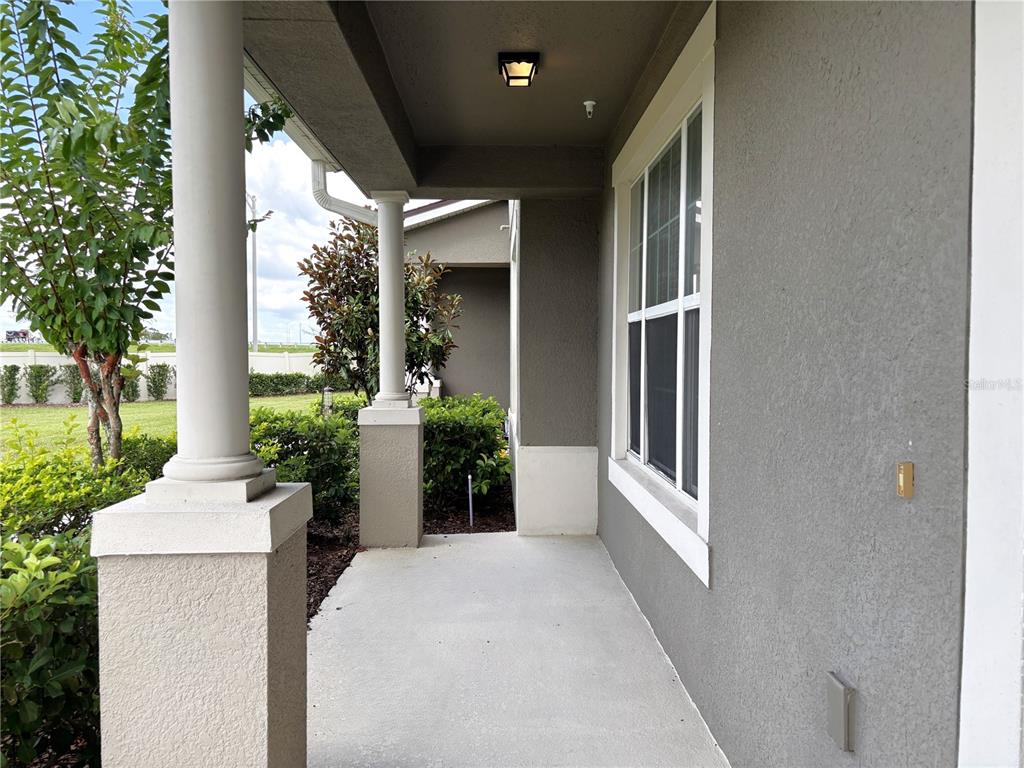 A covered concrete porch features two white columns and a window on a gray wall — 10009 EAGLE ROCK ALLEY, ORLANDO, FL
