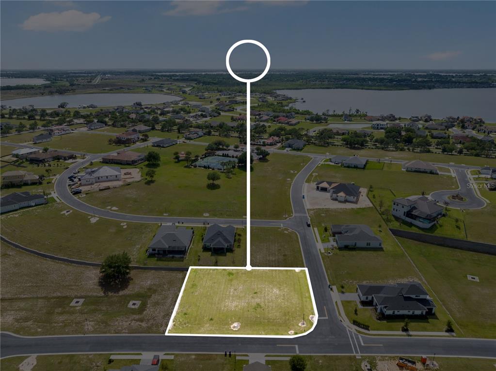 An aerial view shows a vacant, rectangular residential lot situated on a corner street intersection — 285 CALADIUM AVENUE, LAKE ALFRED, FL