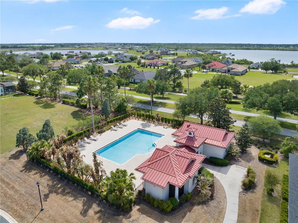 An aerial view shows a community swimming pool with a red metal roof clubhouse — 285 CALADIUM AVENUE, LAKE ALFRED, FL