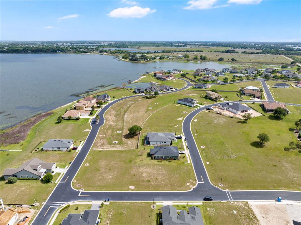 An aerial view shows a residential neighborhood with several houses situated near a large lake — 285 CALADIUM AVENUE, LAKE ALFRED, FL