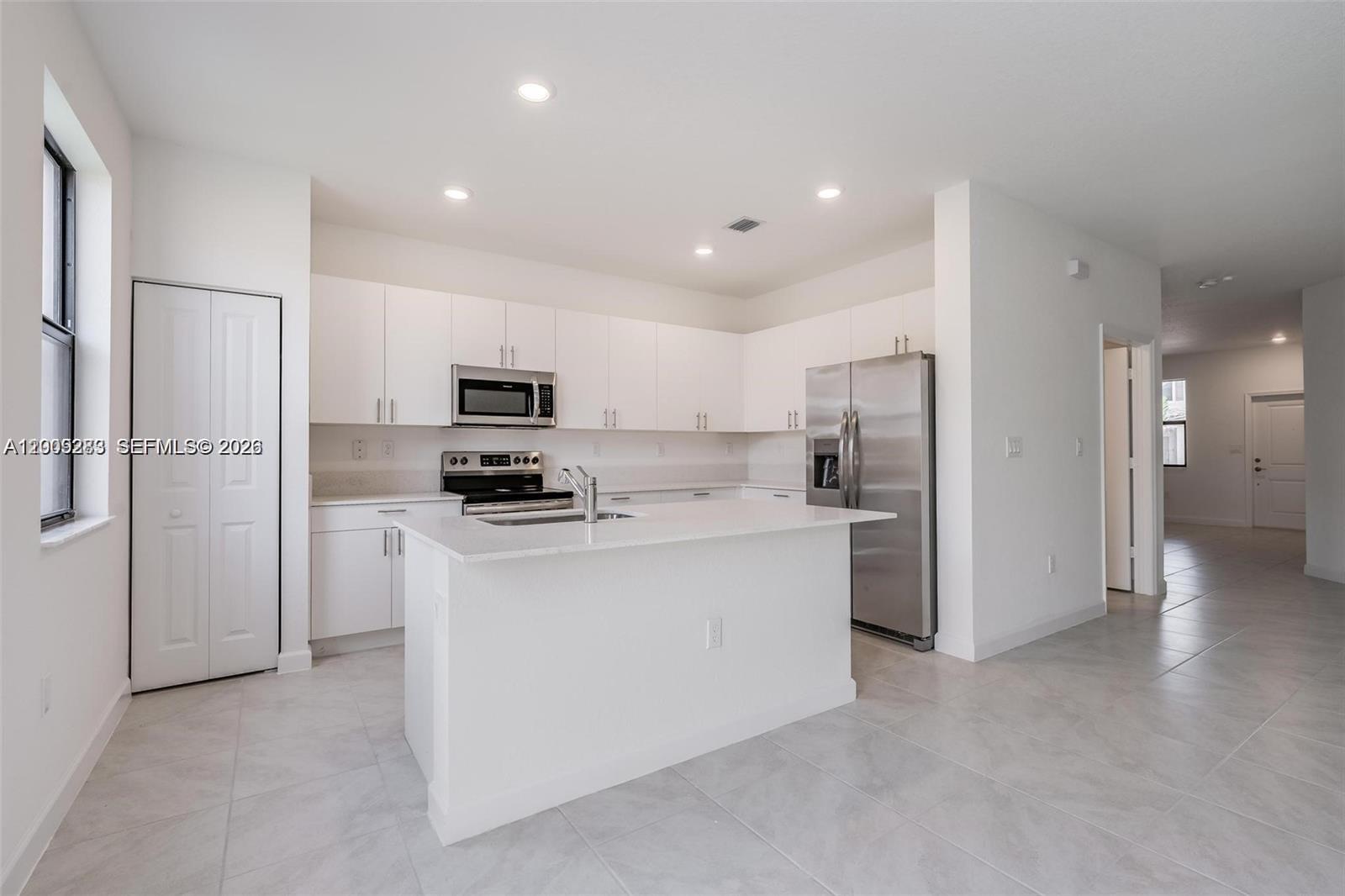 A modern kitchen features white cabinets, stainless steel appliances, and a central island — 23507 SW 129th Path, Homestead FL 33032, HOMESTEAD, FL