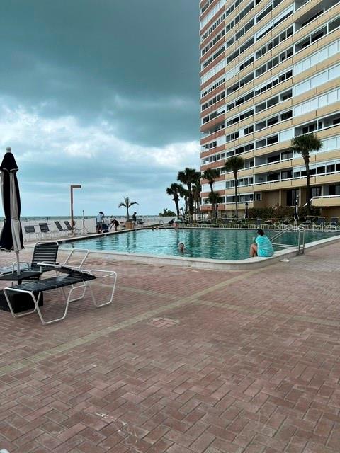 A swimming pool sits on a brick patio next to a tall beachfront residential building — 17920 GULF BOULEVARD UNIT 502, REDINGTON SHORES, FL