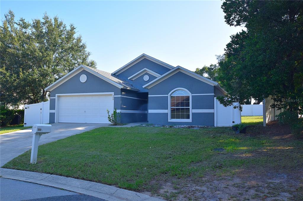 A blue single-story house with a white garage door and a front-facing arched window — 500 LAKE CHARLES DRIVE, DAVENPORT, FL