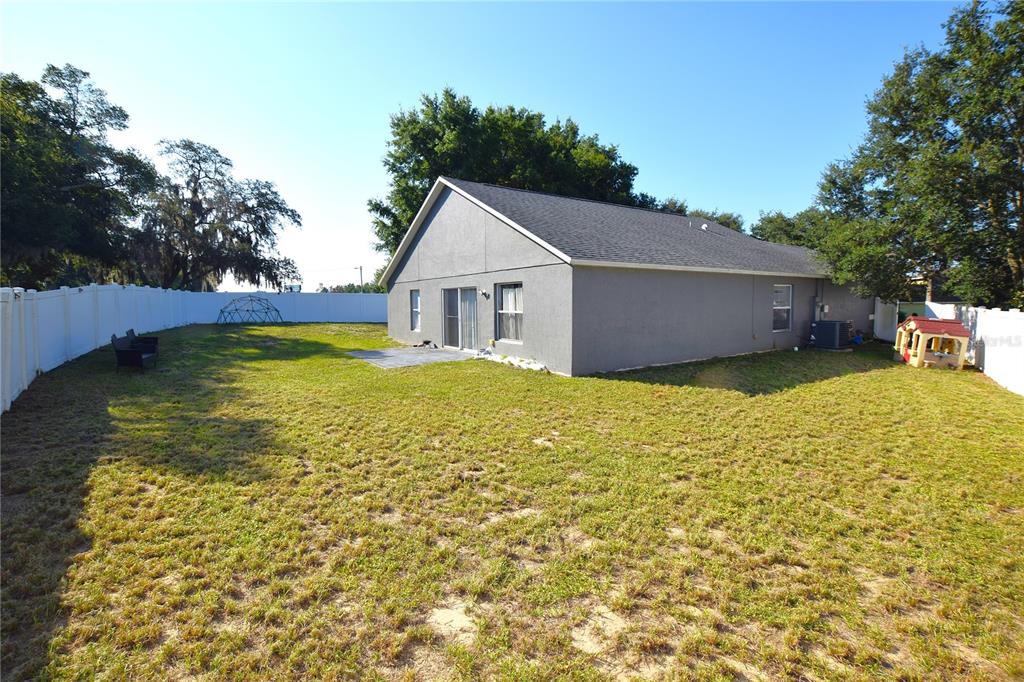 A gray house with a fenced backyard, a small patio, and a grassy lawn — 500 LAKE CHARLES DRIVE, DAVENPORT, FL