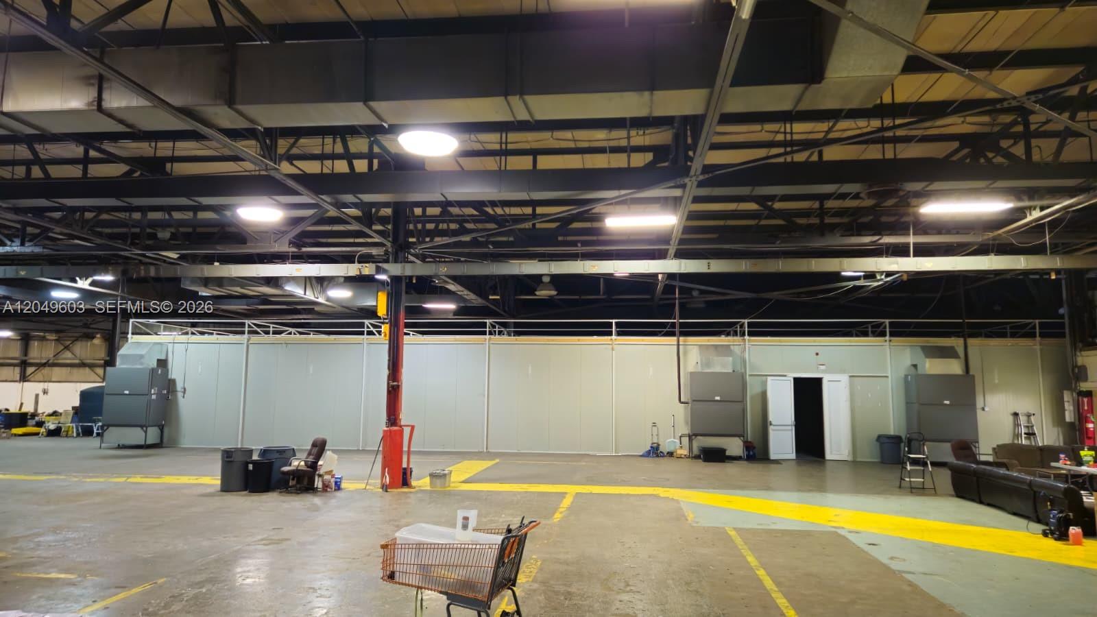 A large, open warehouse space features a long partition wall, exposed ceiling beams, and lighting — 2111 Old Shawnee Rd, OK 74403, OK
