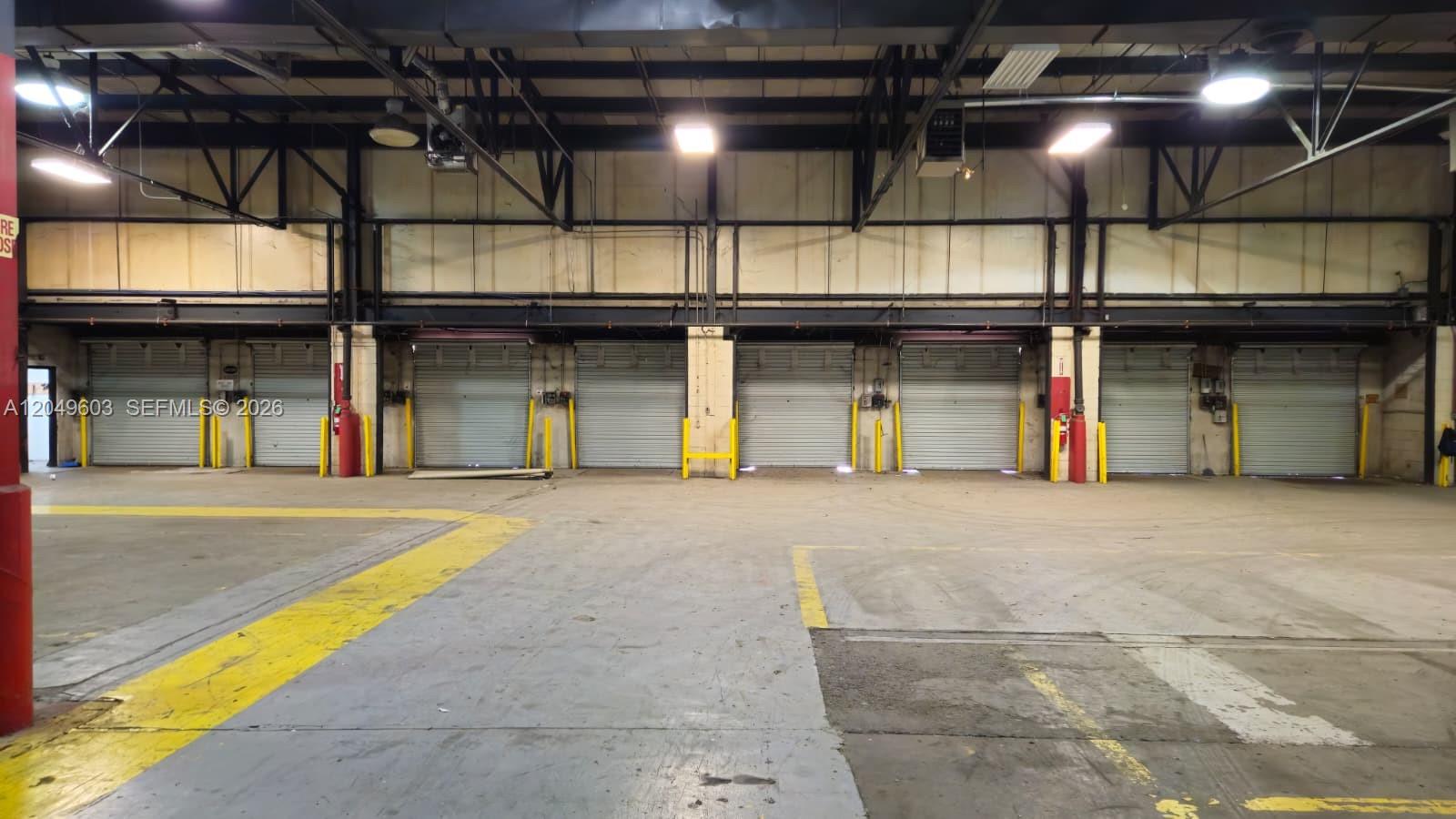 An industrial warehouse interior features a concrete floor and seven closed metal roll-up doors — 2111 Old Shawnee Rd, OK 74403, OK