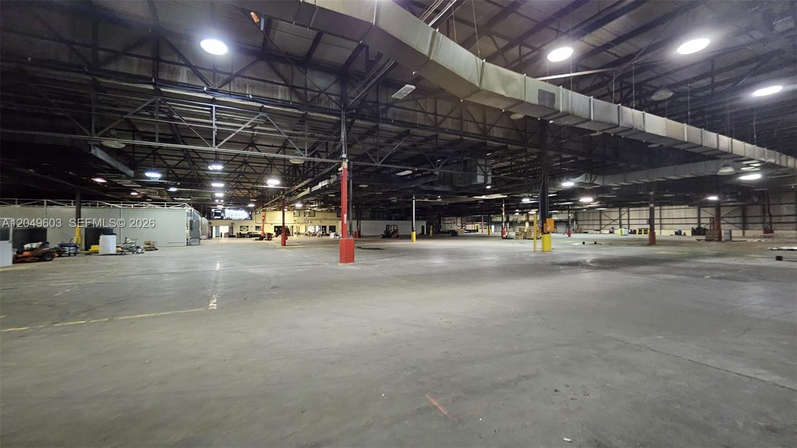 A large, open warehouse space features a concrete floor, exposed ceiling trusses, and overhead lighting — 2111 Old Shawnee Rd, OK 74403, OK