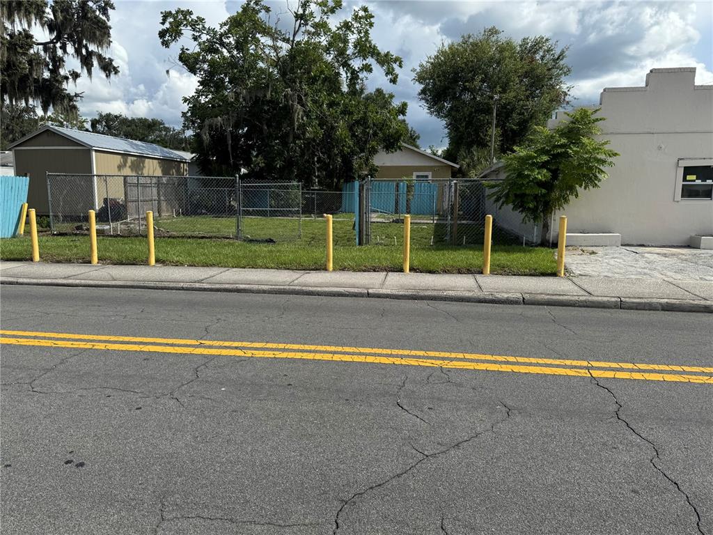 A fenced vacant lot sits between two buildings along a paved street with yellow lines — 618 W 5TH STREET, LAKELAND, FL