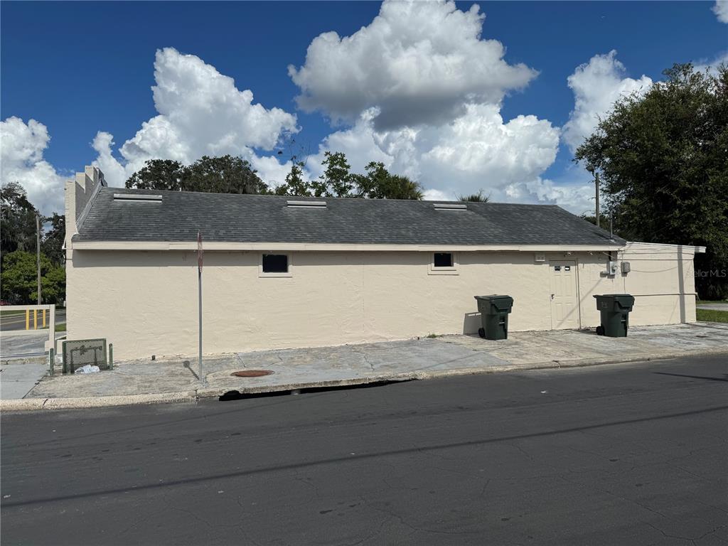 A beige, single-story commercial building with a shingled roof and two trash bins outside — 618 W 5TH STREET, LAKELAND, FL