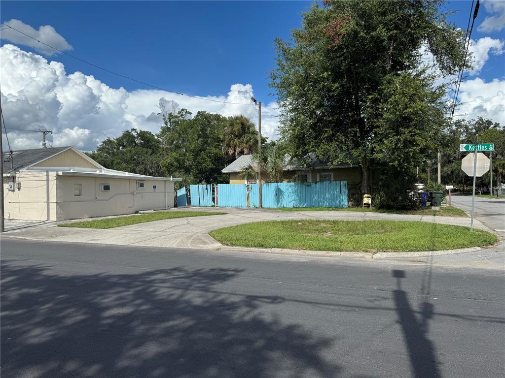 A paved driveway leads to a house partially obscured by a blue wooden fence — 618 W 5TH STREET, LAKELAND, FL