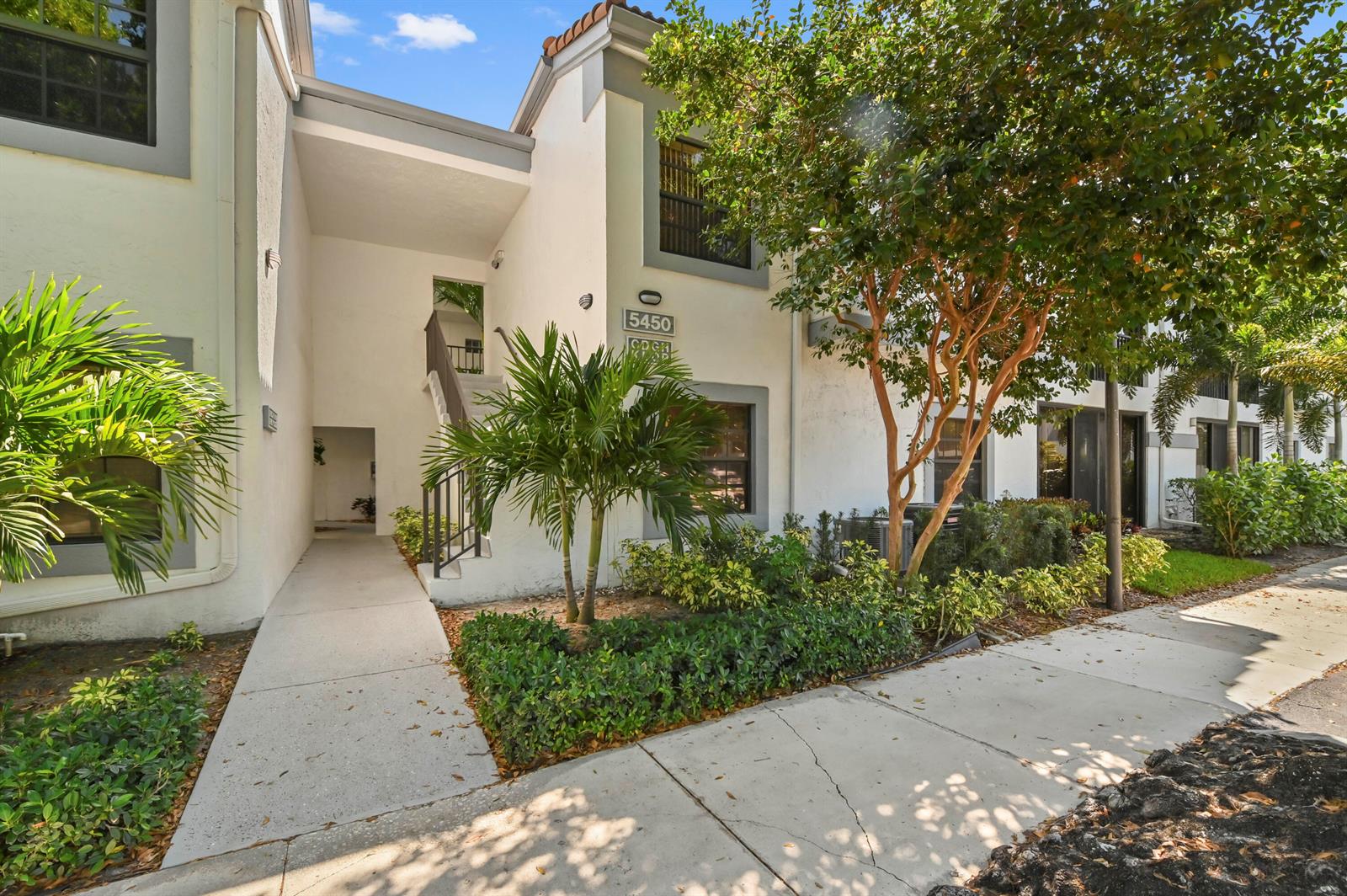 A two-story residential building exterior with a concrete walkway, palm trees, and stairs — 5450 Verona Drive # O, Boynton Beach FL 33437, BOYNTON BEACH, FL