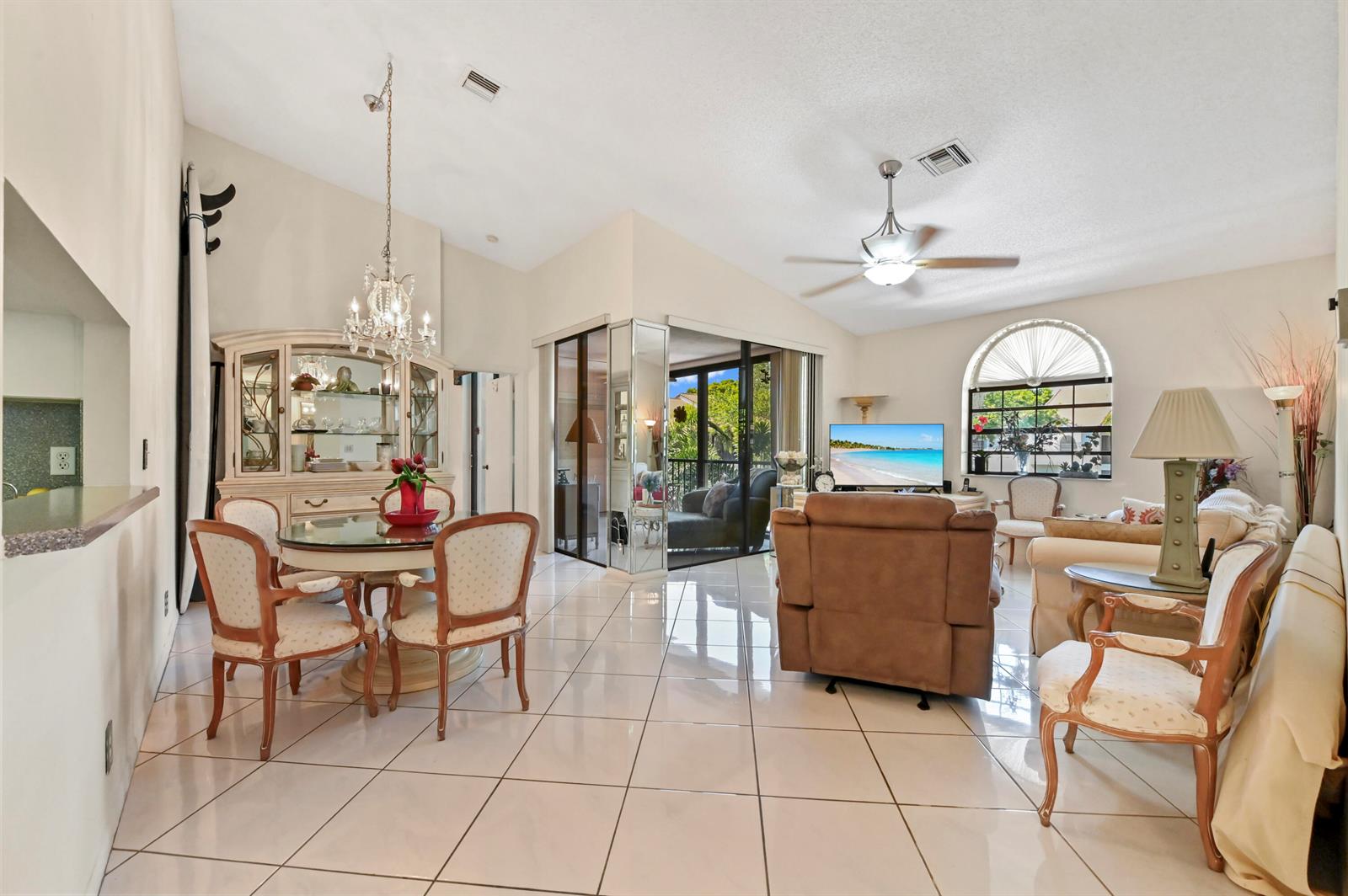 A bright living and dining room with tiled floors, a vaulted ceiling, and glass sliding doors — 5450 Verona Drive # O, Boynton Beach FL 33437, BOYNTON BEACH, FL