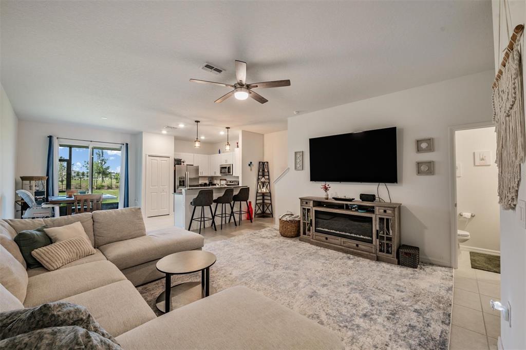 A living room with a sectional sofa, television, fireplace console, and an open-concept kitchen — 9133 BONITA MAR DRIVE, PARRISH, FL