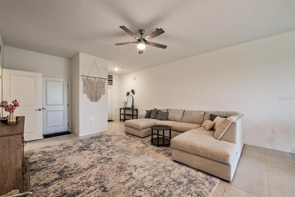 A living room features a beige sectional sofa, a patterned area rug, and a ceiling fan — 9133 BONITA MAR DRIVE, PARRISH, FL