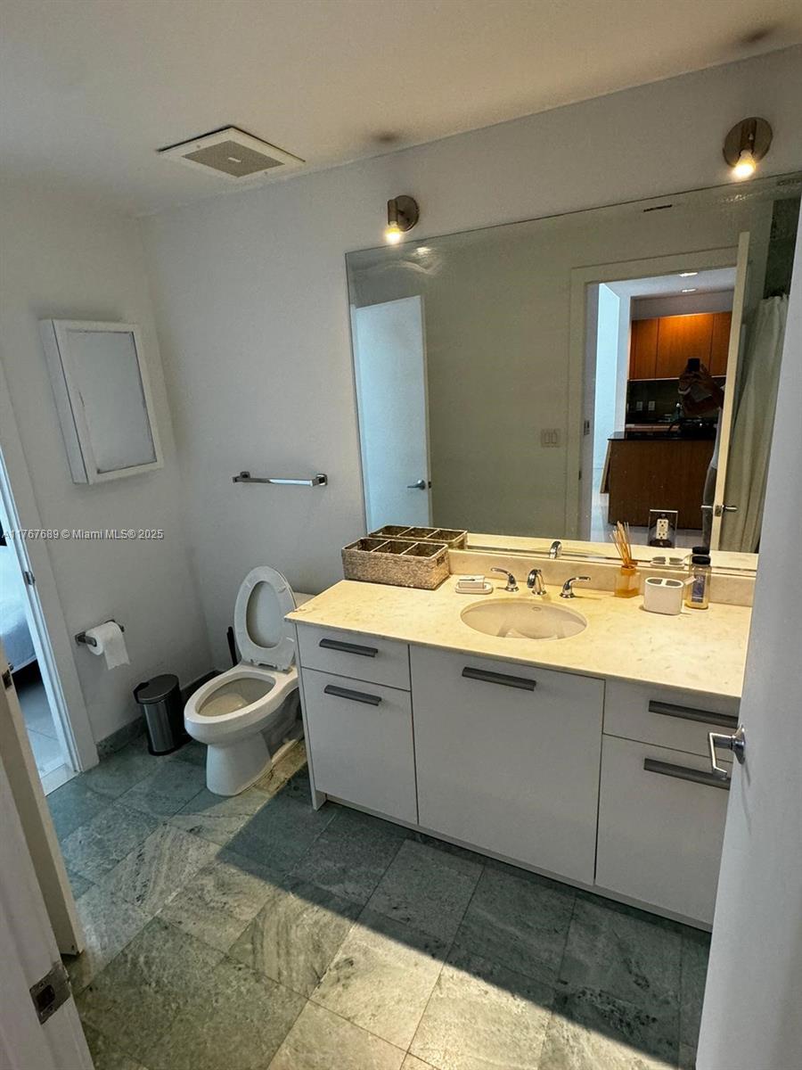 A bathroom features a white vanity with a stone countertop, a toilet, and green tile flooring — 1050 Brickell Ave # 2908, Miami FL 33131, MIAMI, FL