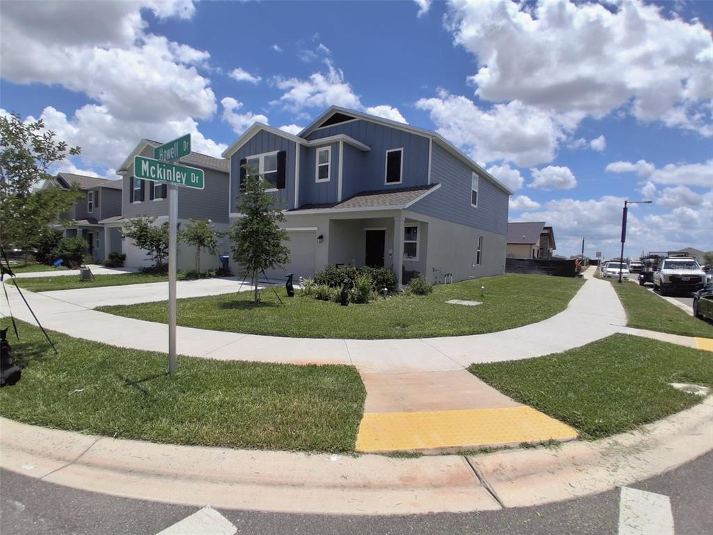 A two-story blue house sits on a corner lot at a street intersection — 3486 HOWELL DRIVE, LAKE WALES, FL