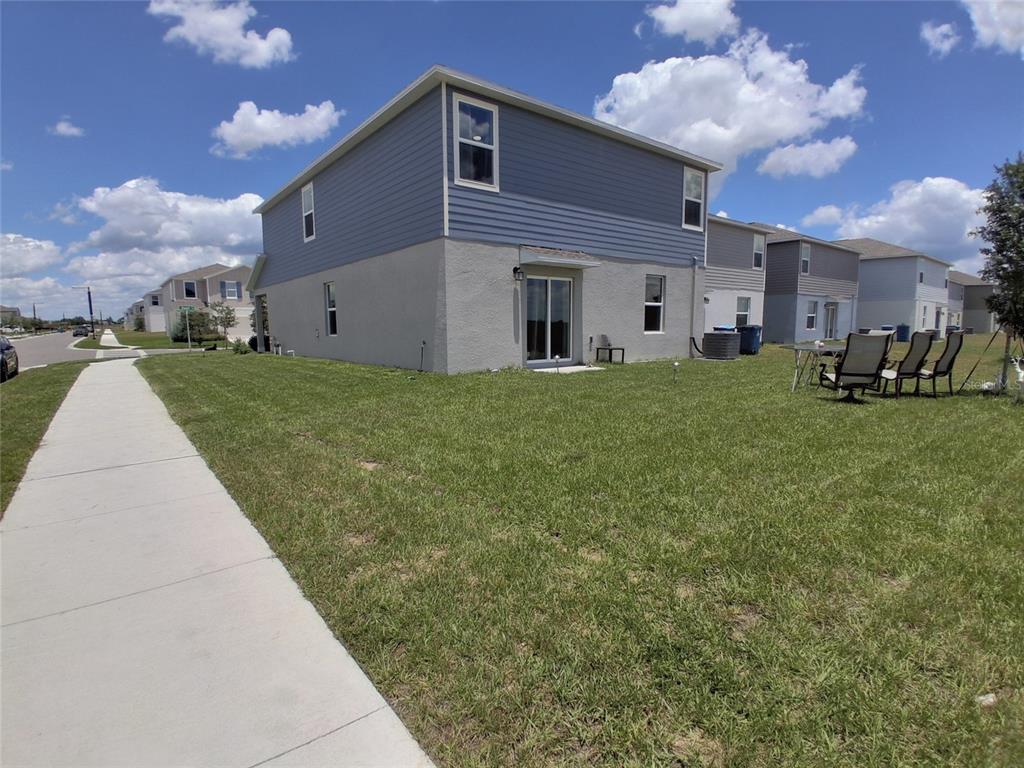 A two-story house with blue siding and stucco exterior features a backyard and patio — 3486 HOWELL DRIVE, LAKE WALES, FL