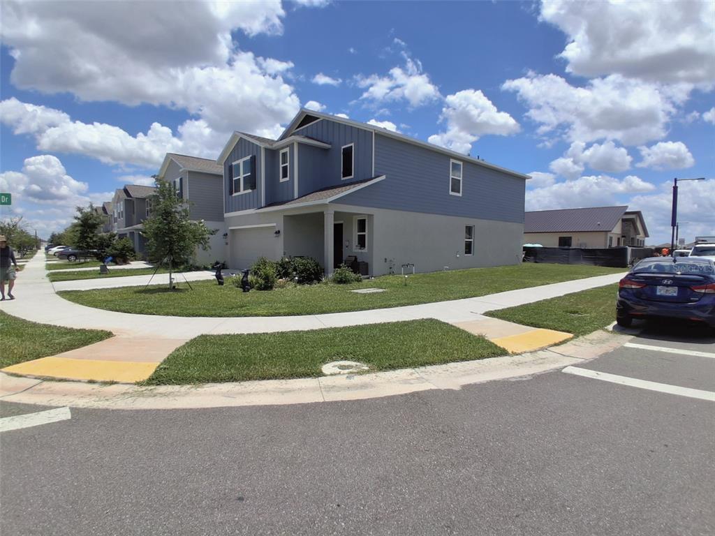 A two-story house with blue siding and a concrete exterior sits on a corner lot — 3486 HOWELL DRIVE, LAKE WALES, FL