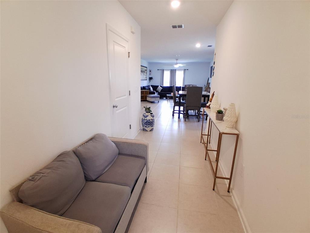 A hallway with a sofa and console table leads to an open-concept dining and living area — 3486 HOWELL DRIVE, LAKE WALES, FL