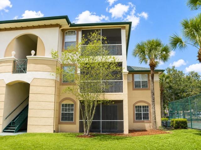 A three-story apartment building with tan stucco walls, screened balconies, and an exterior staircase — 17102 CARRINGTON PARK DRIVE UNIT 302, TAMPA, FL