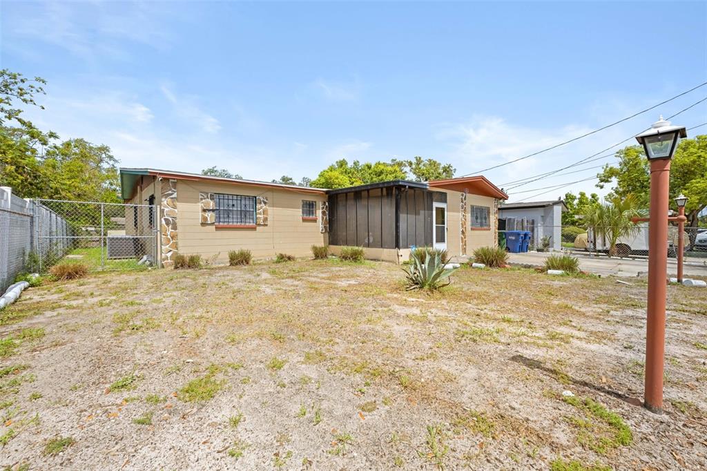 A single-story house with tan siding, a screened-in porch, and a sandy front yard — 10412 N ALTMAN STREET, TAMPA, FL