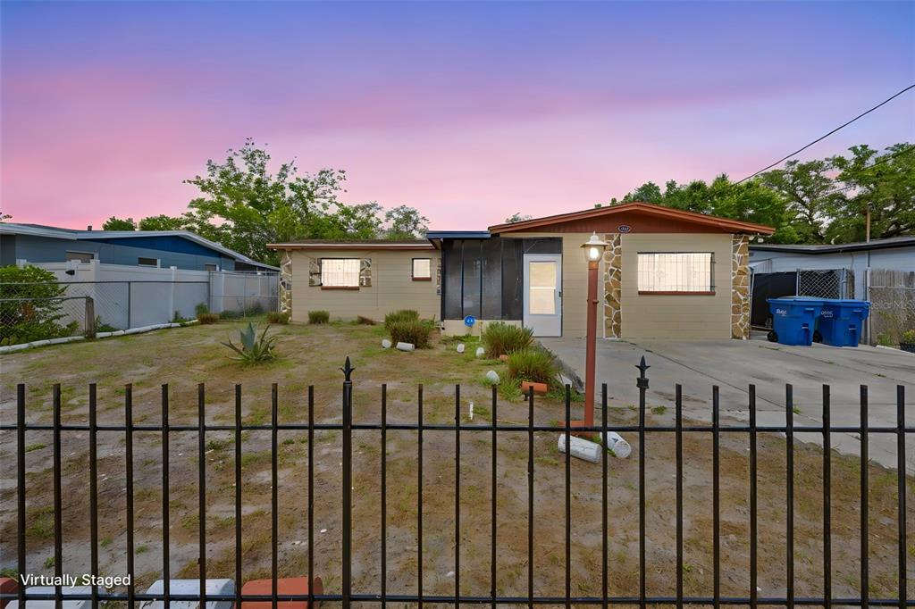 A single-story house with a tan exterior, a front porch, and a metal fence — 10412 N ALTMAN STREET, TAMPA, FL