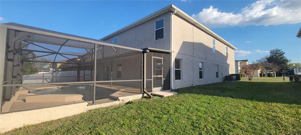 A two-story house features a screened-in pool enclosure and a grassy backyard — 15461 GALBI DRIVE, ORLANDO, FL