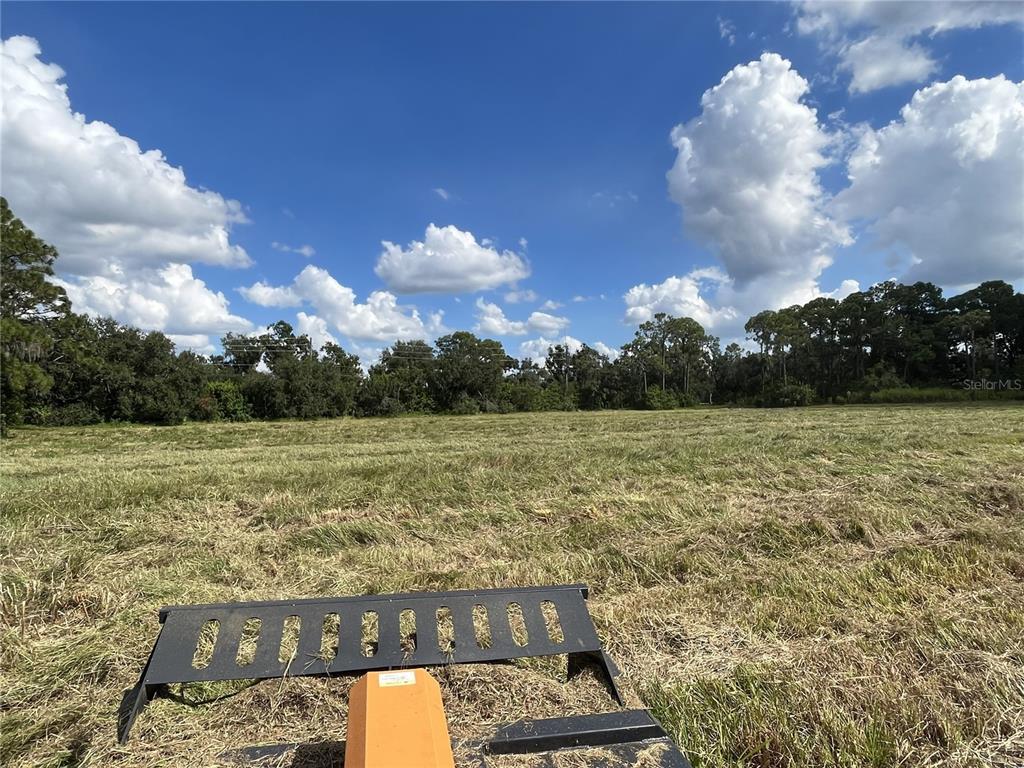 A view of a large, mowed grassy field with a tractor attachment in the foreground — SE 24TH AVENUE, RUSKIN, FL