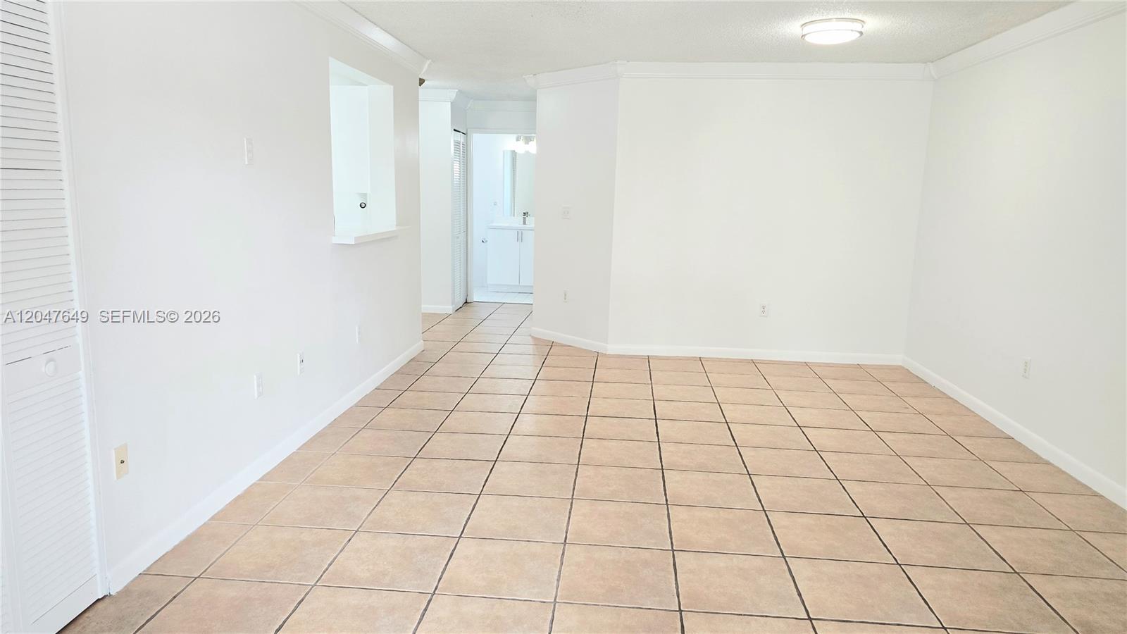 A bright, empty room features white walls, tan tile flooring, and a doorway leading inside — 15771 SW 137th Ave # 203, Miami FL 33177, MIAMI, FL
