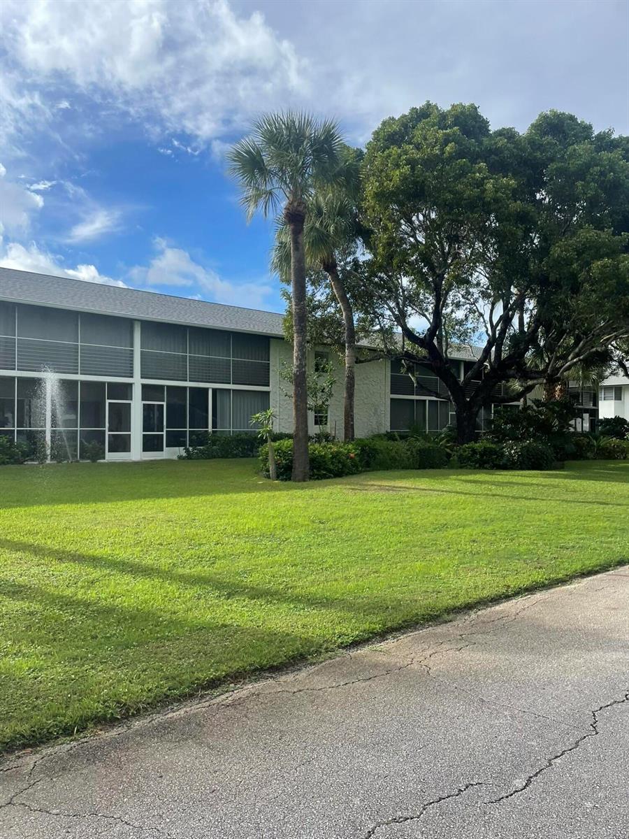 A two-story apartment building with screened-in porches sits behind a large green lawn — 2 Garden Street # 106m, Tequesta FL 33469, TEQUESTA, FL