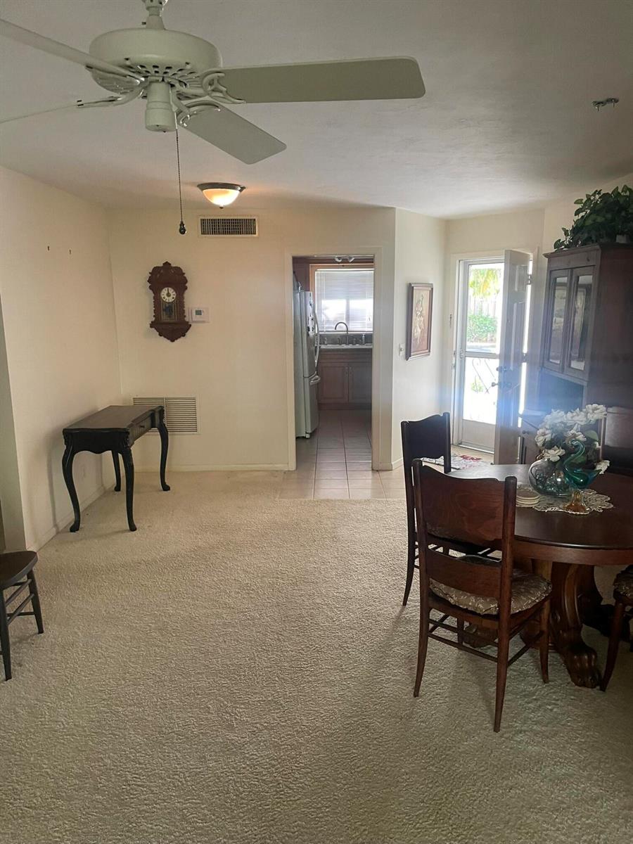 A dining area features carpeted flooring, a ceiling fan, a round table, and a wall clock — 2 Garden Street # 106m, Tequesta FL 33469, TEQUESTA, FL