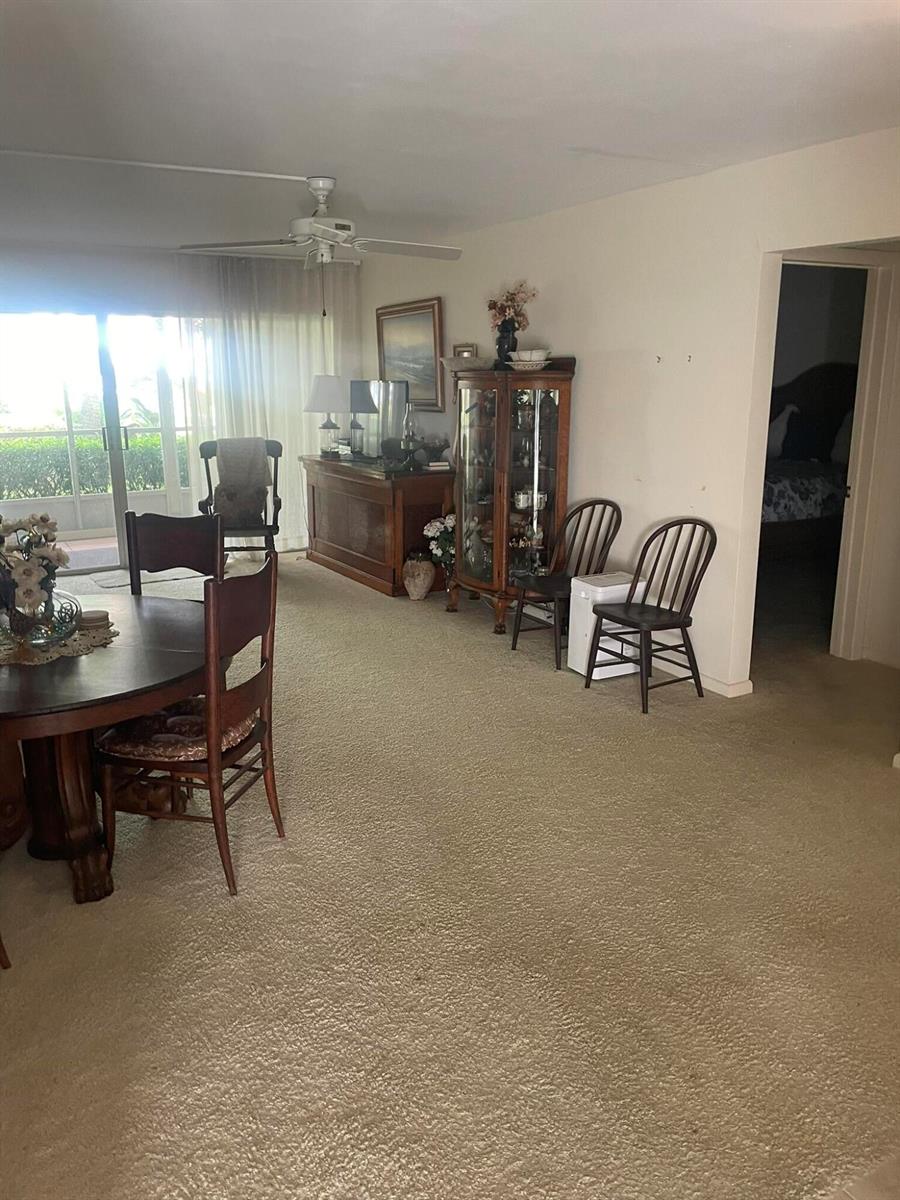 A dining area with carpeted floors, a round wooden table, and a glass display cabinet — 2 Garden Street # 106m, Tequesta FL 33469, TEQUESTA, FL