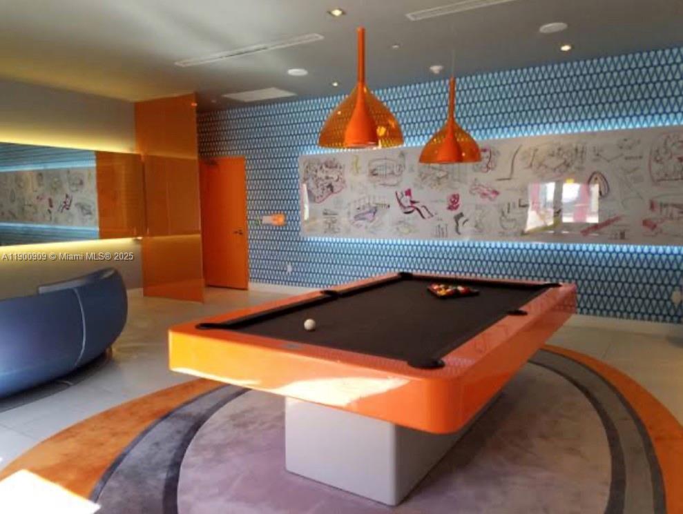 A game room features a bright orange pool table, matching pendant lights, and patterned wallpaper — 31 SE 6th St # 2508, Miami FL 33131, MIAMI, FL