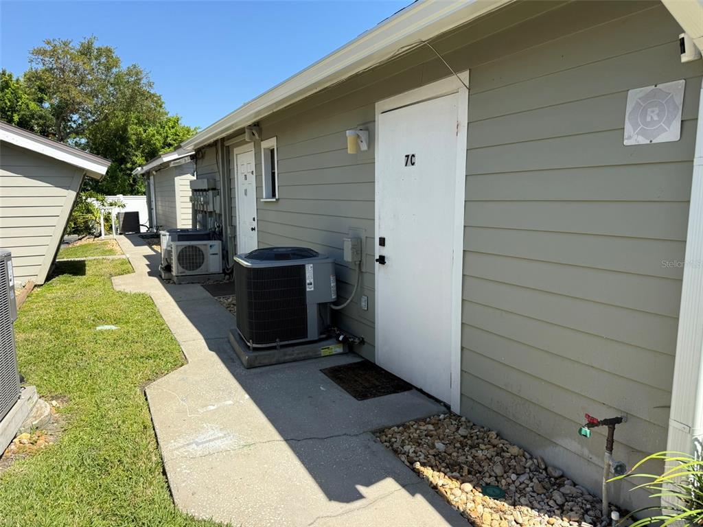 The exterior of a residential building features a white door labeled 7C and an HVAC unit — 10225 ULMERTON ROAD UNIT 7C, LARGO, FL