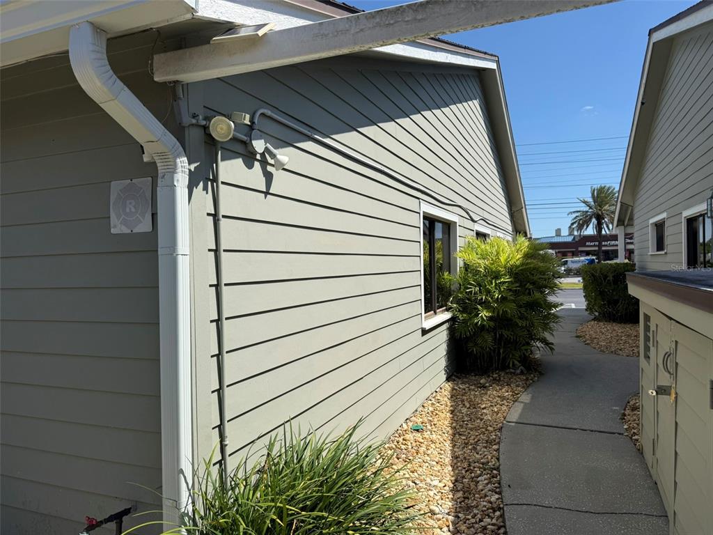 A side view of a building exterior with light green siding, a walkway, and landscaping — 10225 ULMERTON ROAD UNIT 7C, LARGO, FL